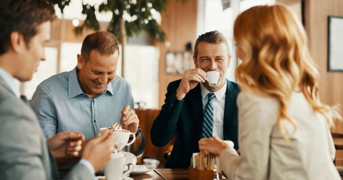 Colleagues laughing together drinking coffee